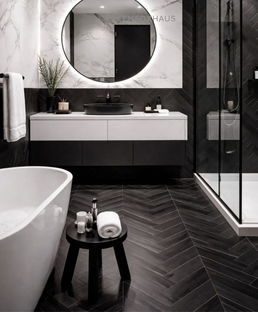 Mẫu thiết kế phòng tắm sử dụng gạch giả gỗ màu đen lát xương cá cho nền kết hợp cùng gạch vân đá marble trắng ốp tường khu vực lavabo tạo nên sự tương phản tinh tế giữa ấm và lạnh, sáng và tối. Cách phối này giúp không gian vừa cá tính, hiện đại lại vẫn sạch sẽ và sang trọng, rất phù hợp với phòng tắm phong cách boutique hotel hoặc nhà phố cao cấp.