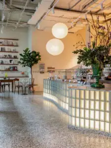 Gạch kính lấy sáng ốp quầy cà phê kết hợp sàn terrazzo trong không gian thương mại hiện đại.