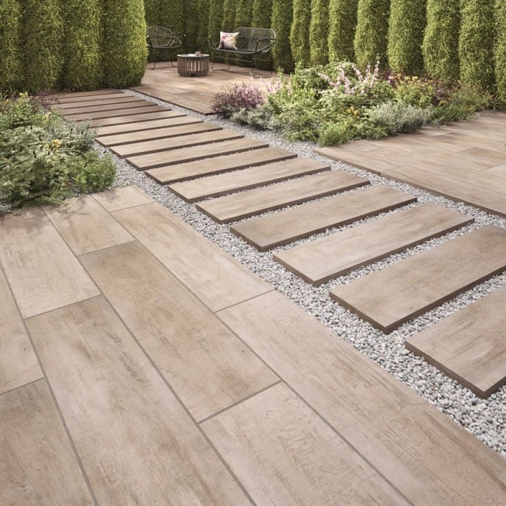 Gạch giả gỗ kích thước dài được sử dụng cho lối đi sân vườn, kết hợp sỏi trắng và cây xanh tạo bố cục gọn gàng, dễ vệ sinh.