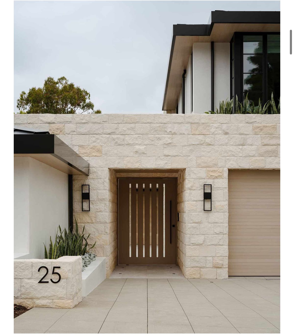 Tường cổng vân đá sáng – sáng mặt tiền, hợp khung cửa/kim loại đen.