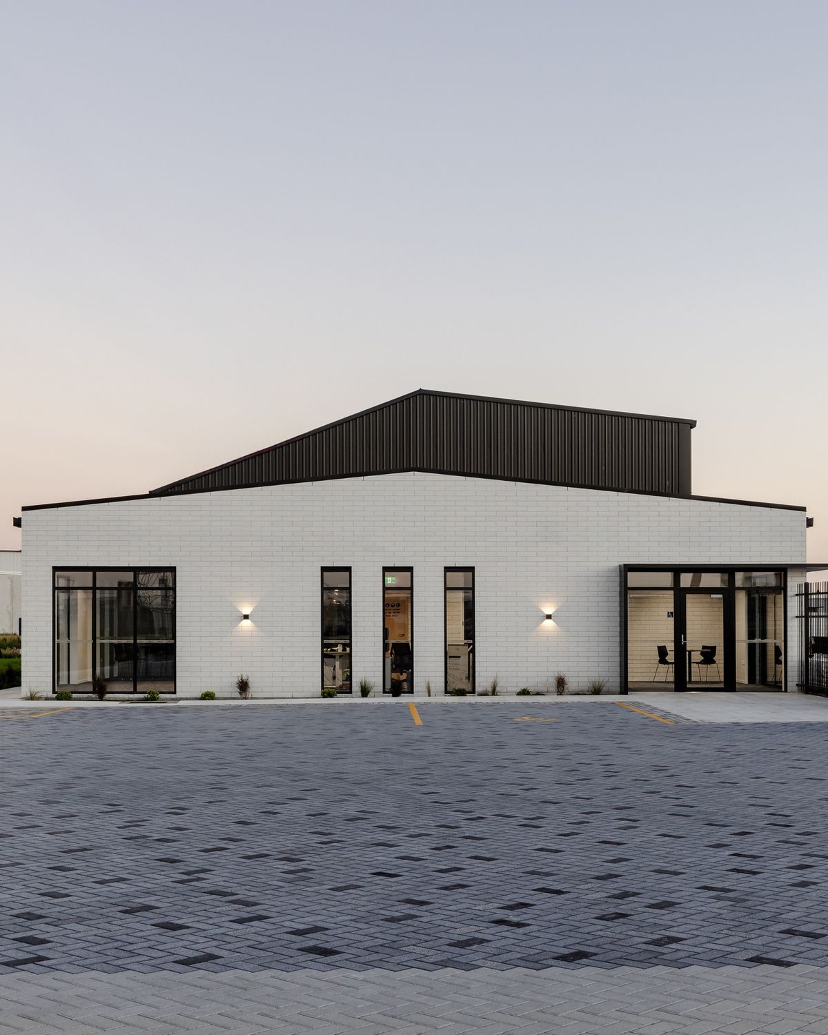 Mặt tiền ốp gạch subway trắng xếp ngang truyền thống, tạo tổng thể tối giản nhưng nổi bật với hệ khung cửa đen tương phản mạnh mẽ.