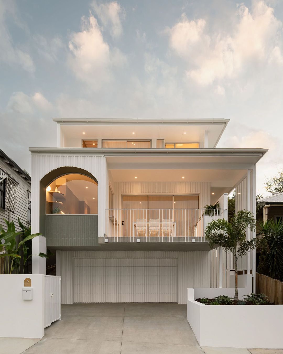 Thiết kế nhà phố 2 tầng sử dụng gạch subway trắng mờ, phối lam đứng tạo điểm nhấn chiều sâu cho mặt tiền.