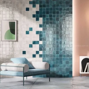 Mảng tường gạch vuông chuyển sắc độ từ trắng sang xanh ngọc, kết hợp ghế băng hiện đại trong không gian nội thất tối giản.