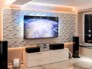 Mảng tường TV ốp gạch mosaic tông xám trắng kết hợp đèn LED hắt sáng trong phòng khách hiện đại.